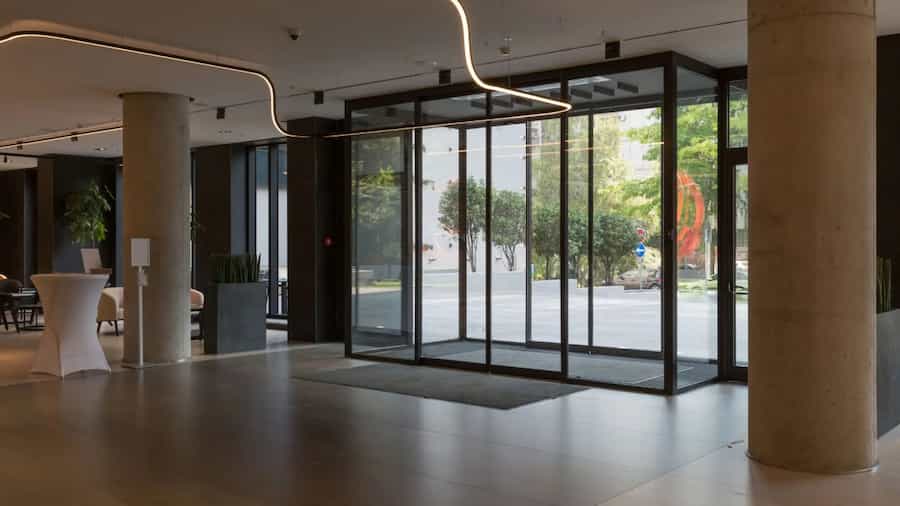 automatyczne drzwi przesuwne z czujnikiem ruchu i czarnym profilem aluminiowym w nowoczesnym holu biznesowym