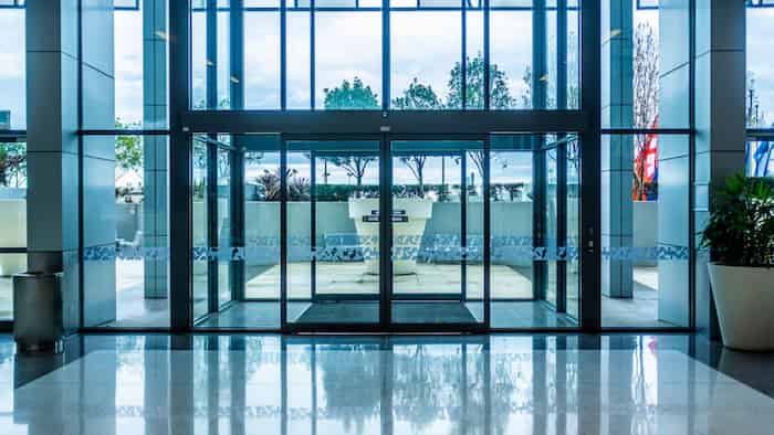 automatyczne szklane drzwi przesuwne z matowionym wzorem w przestronnym przeszklonym holu