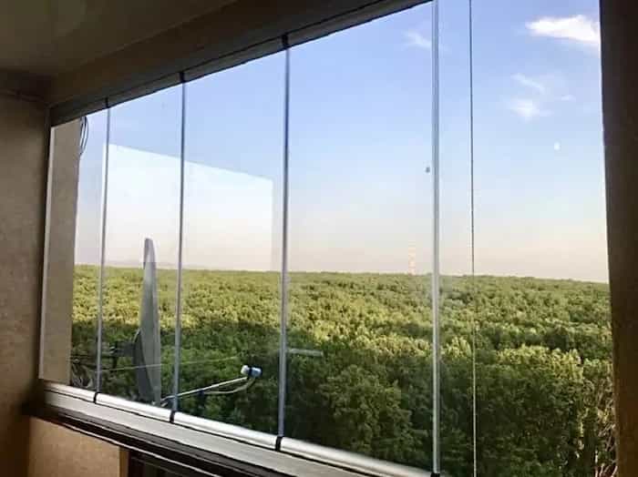 panoramiczne bezramowe przeszklenie loggii z widokiem na las i horyzont w słoneczny dzień