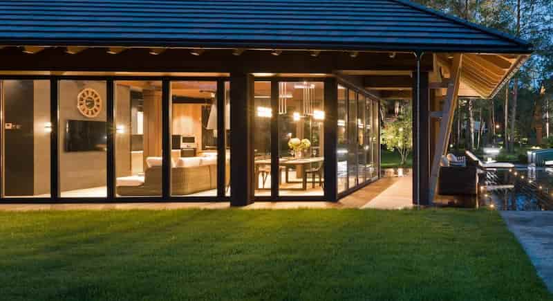 panoramiczne przeszklenie tarasu i strefy wypoczynkowej nowoczesnego domu z wieczornym oświetleniem