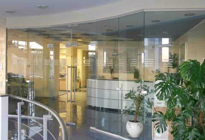 duża całoszklana ścianka biurowa z drzwiami rozwiernymi i matowymi poziomymi pasami wewnątrz pomieszczenia