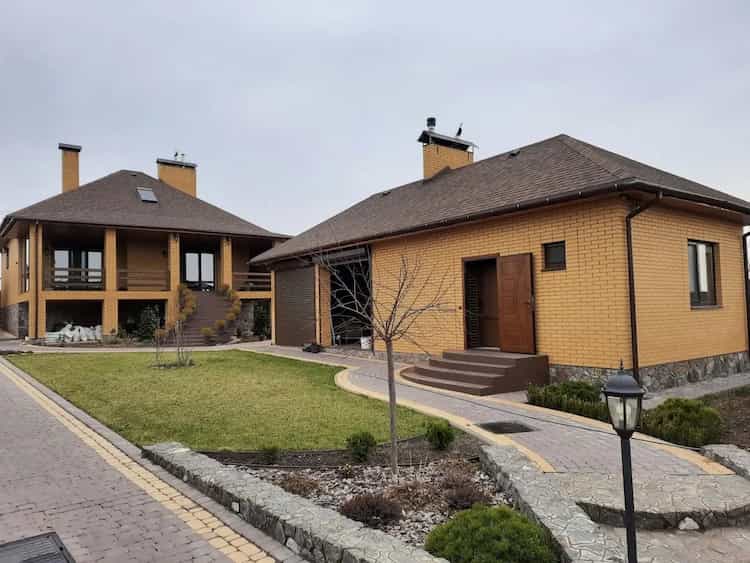 panoramiczne i standardowe okna plastikowe w okleinie drewnopodobnej na elewacji nowoczesnego domu z cegły